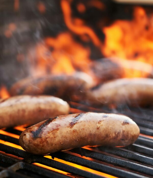 bratwurst sausage barbecue cooking on grill top with flames